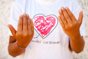 Manos de un niño con cardiopatía sobre la camiseta de Menudos Corazones.