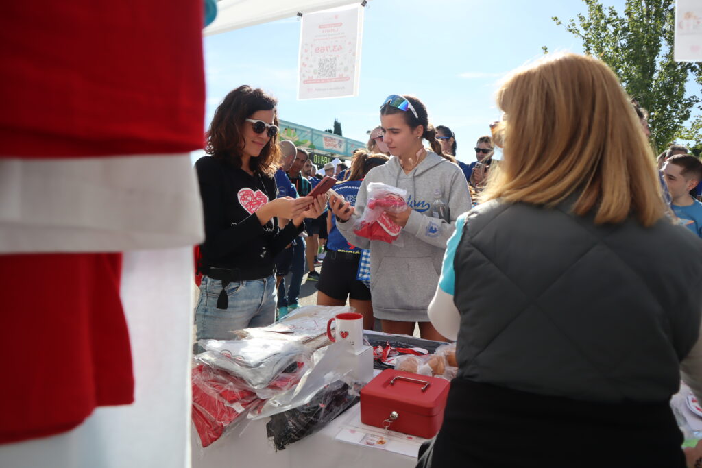 Una corredora adquiere productos solidarios de la Fundación, durante la Carrera Solidaria Menudos Corazones